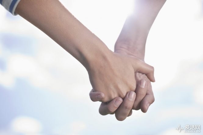 Close-up of a couple holding hands in field